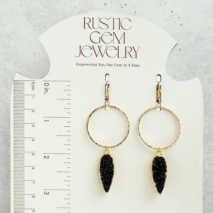 Gold hoop earrings with black dangling stones on a &