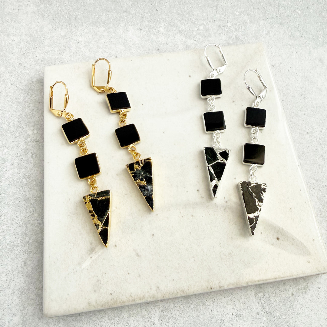 Pair of black and gold earrings on a marble surface