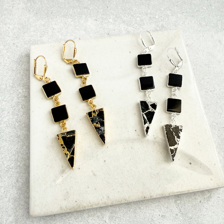 Pair of black and gold earrings on a marble surface