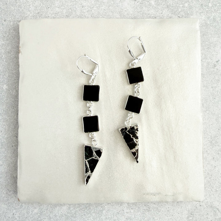 Pair of earrings with black and white geometric designs on a light gray background