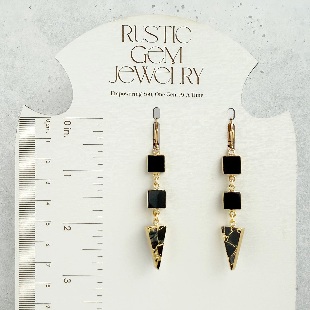 Pair of black and gold earrings on a &