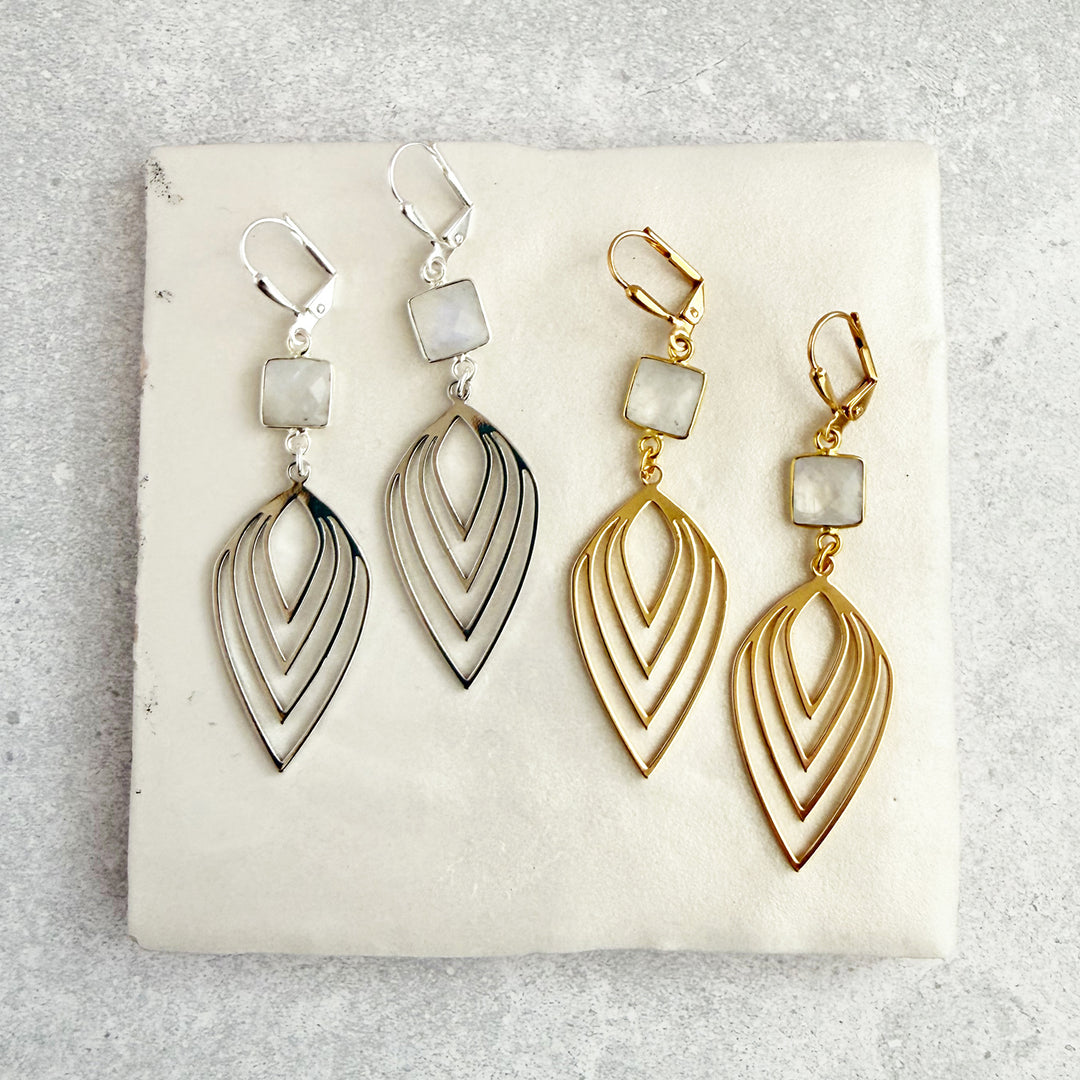 Pair of gold and silver earrings on a white stone surface