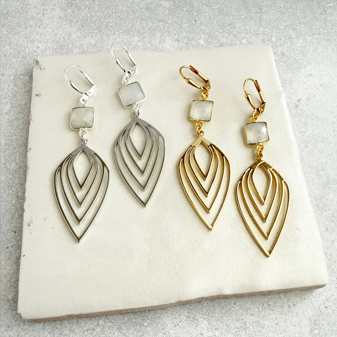 Pair of gold and silver earrings on a white stone surface
