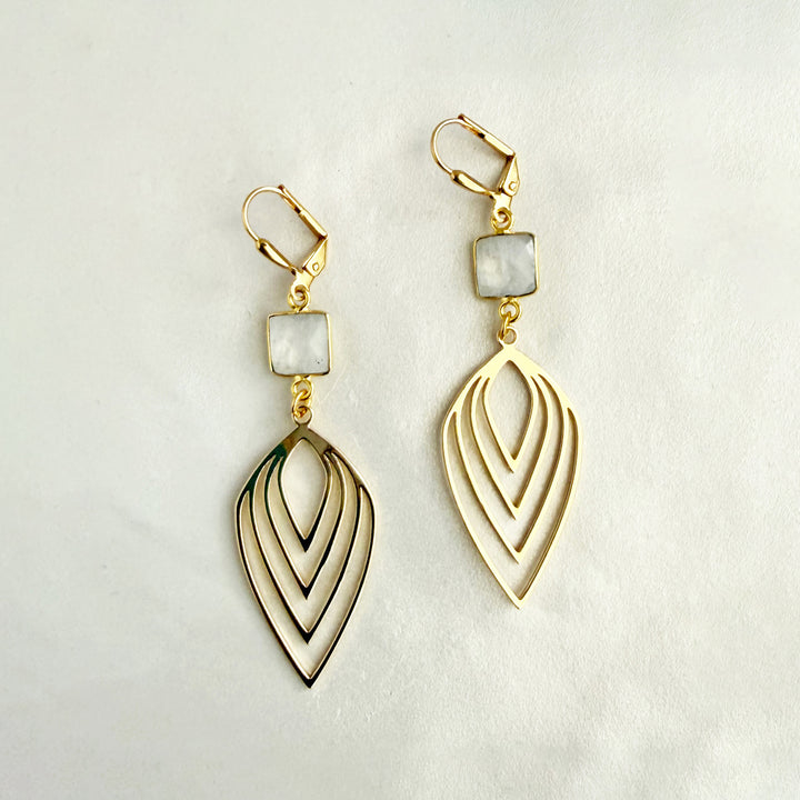 Gold earrings with a geometric design on a light background