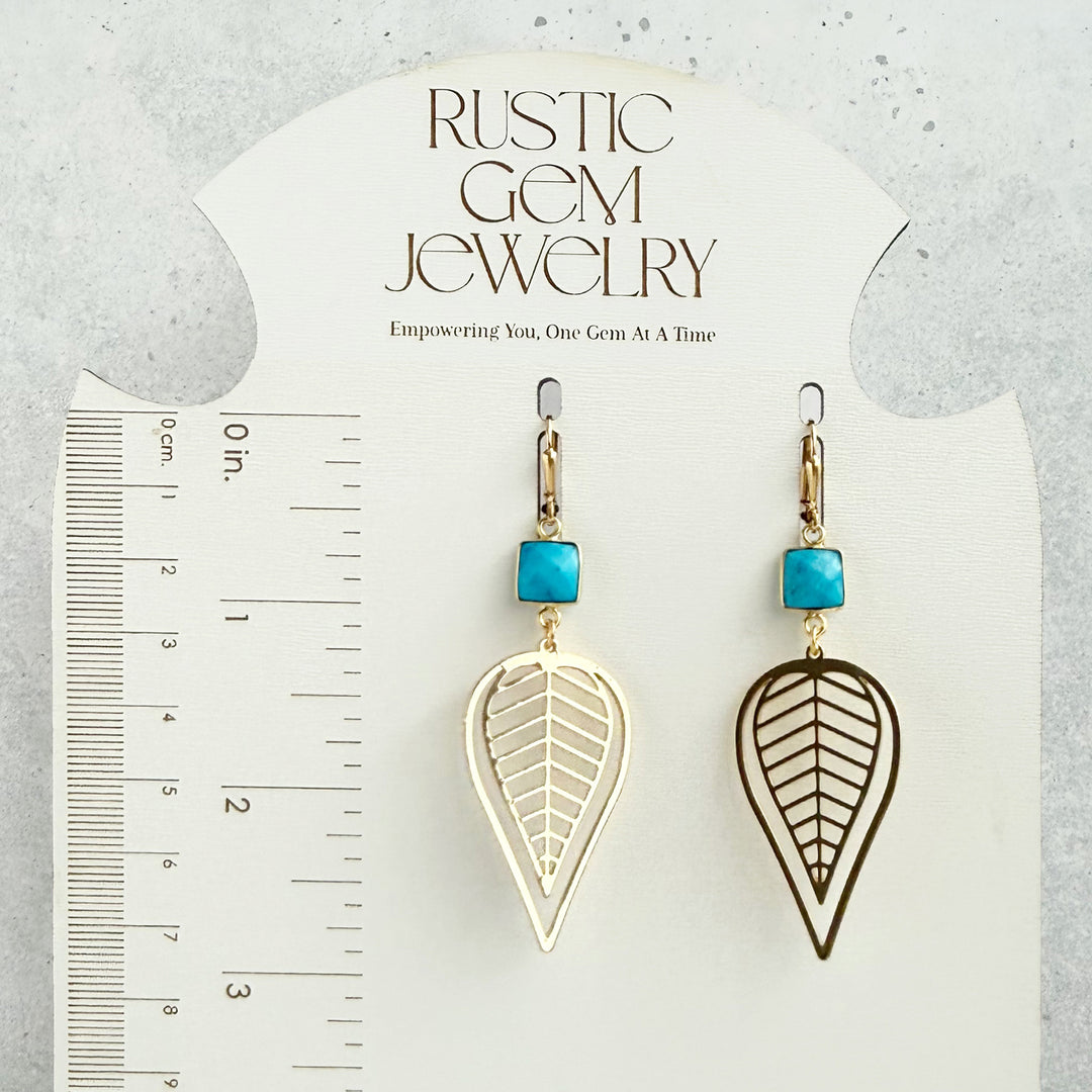 Pair of earrings with leaf designs and turquoise stones on a &