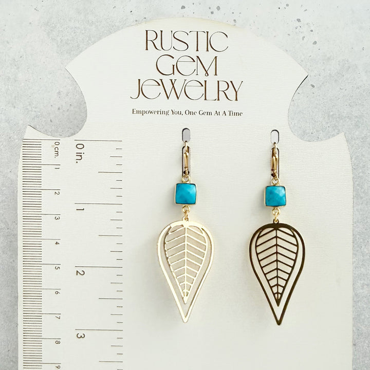 Pair of earrings with leaf designs and turquoise stones on a &